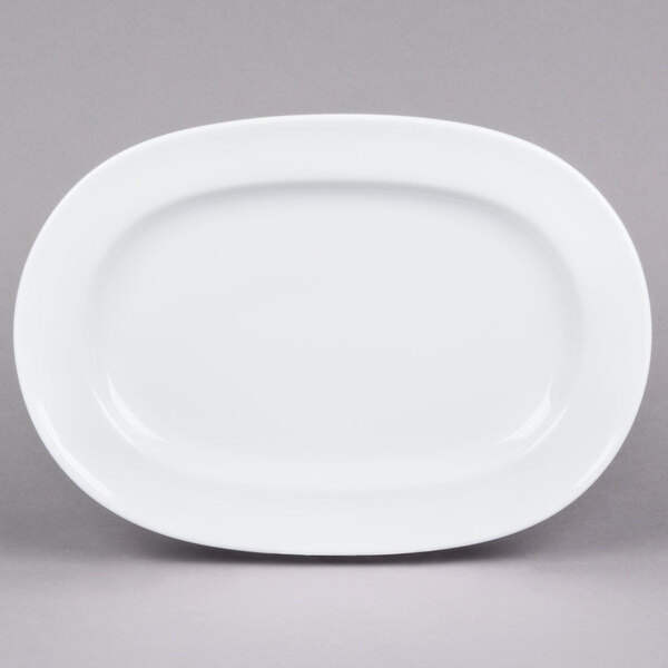 An Arcoroc white oval porcelain platter with a rim on a gray surface.