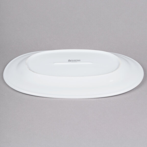 An Arcoroc white oval porcelain platter with black text reading "Arc Cardinal" on the bottom.