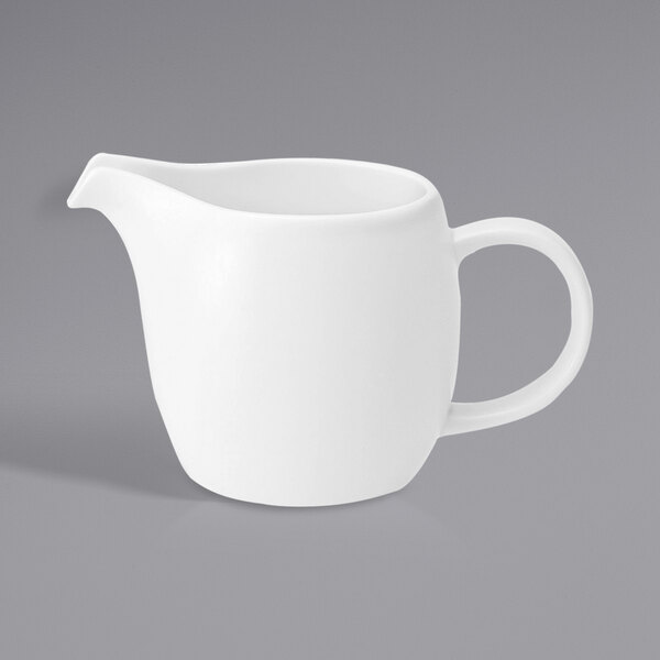 A white porcelain creamer pitcher with a handle.