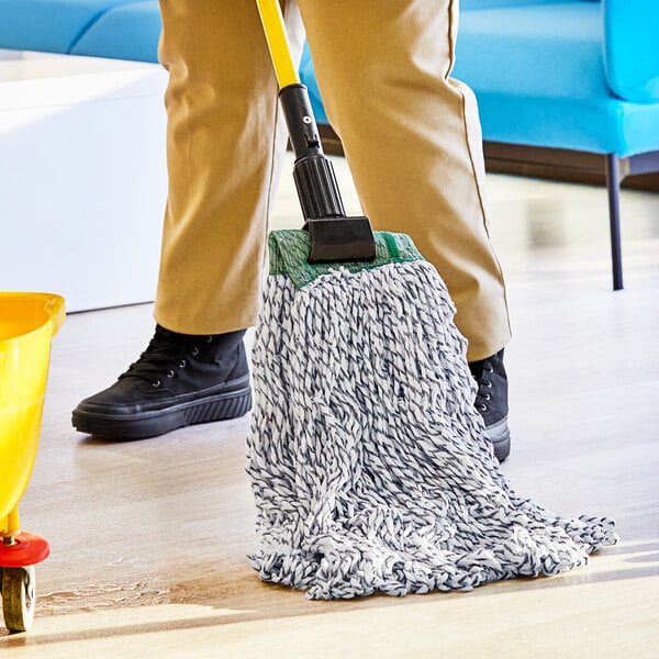 A person holding a Lavex blue and white mop with a yellow handle.