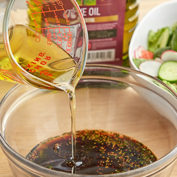 Liquid being poured from a measuring cup into a bowl of food.