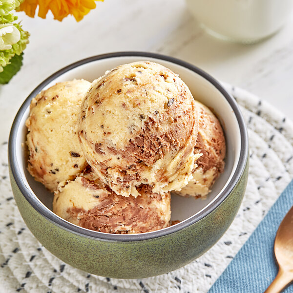 A bowl of Cookie Dough Bliss vegan mochatella cookie dough on a table with a bowl of ice cream.