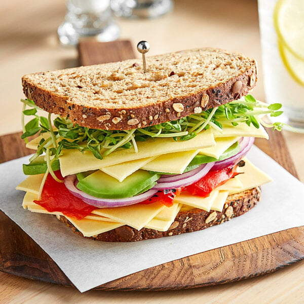 A sandwich on a cutting board with Field Roast Chao Creamy Original Cheese, lettuce, and tomato.