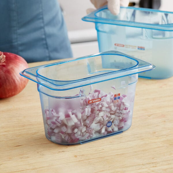 A close-up of a blue Araven plastic food pan filled with chopped onions.