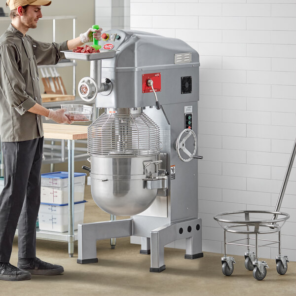 A man using an Avantco commercial floor mixer with a metal bowl.