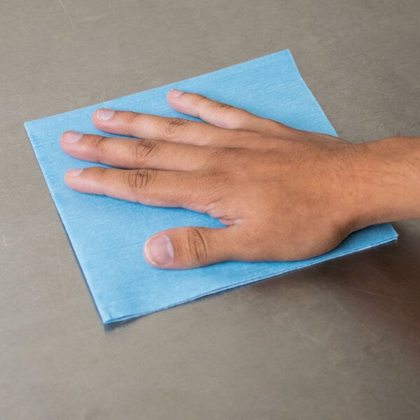 A hand using a blue Chicopee Veraclean wiper on a blue surface.