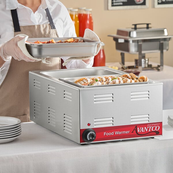 A stainless steel Avantco electric countertop food warmer with a control knob and food pans, designed for keeping food hot at buffets or catering events.