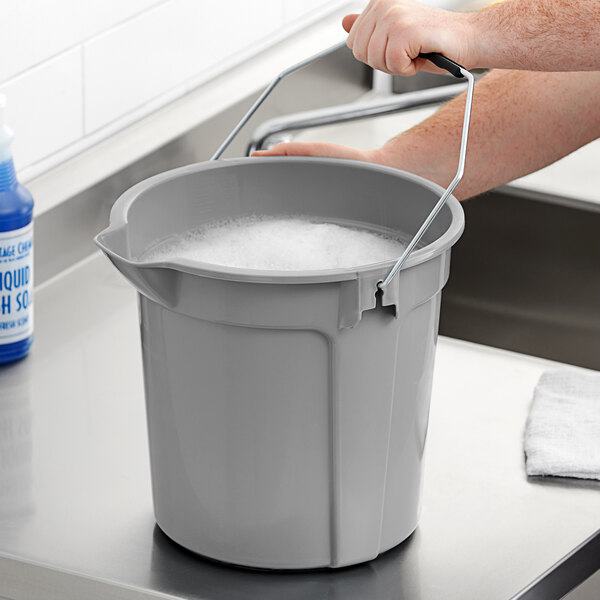 A person washing a Lavex bucket on a counter.