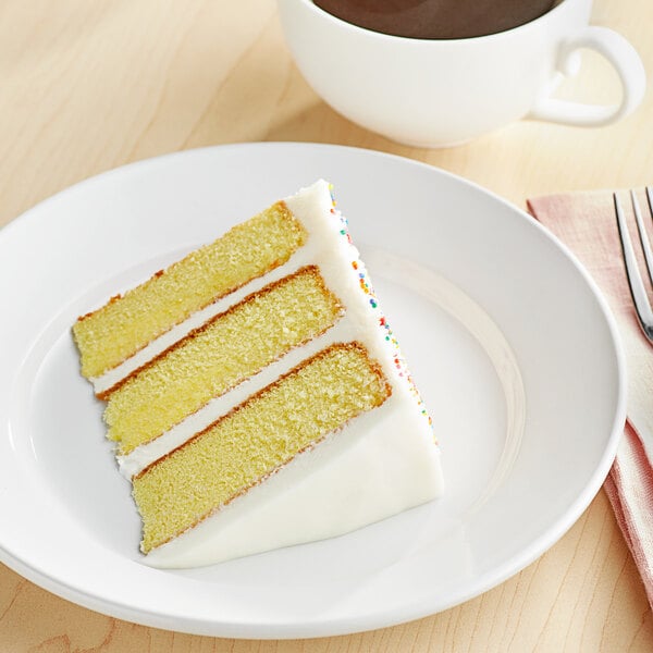 A slice of cake on a plate next to a cup of coffee with a bag of Whole Milk Powder Blend in the background.