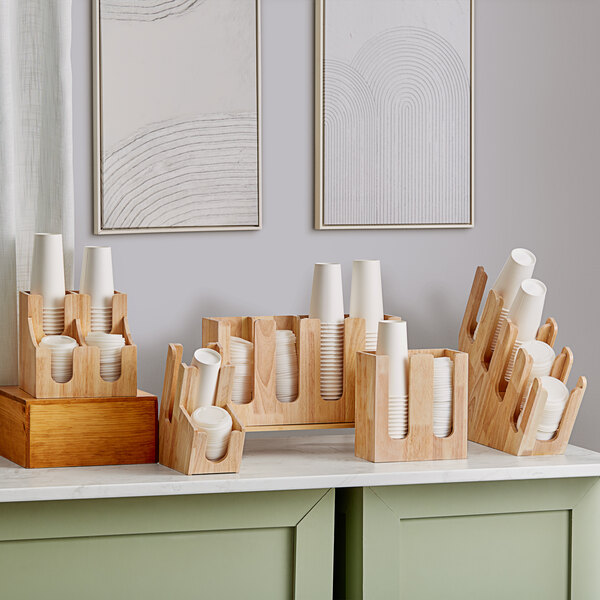 An Acopa wood cup and lid organizer holding paper cups on a counter.