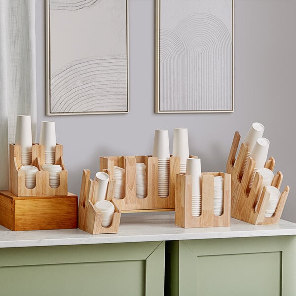 An Acopa wood cup and lid organizer on a counter holding paper cups.