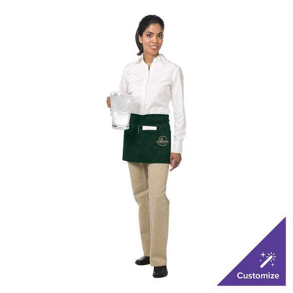 A woman wearing a Chef Revival hunter green waist apron holding a glass of ice.