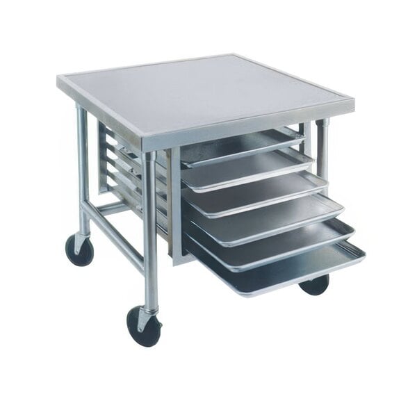 A stainless steel mobile mixer table with tray slides holding metal trays.