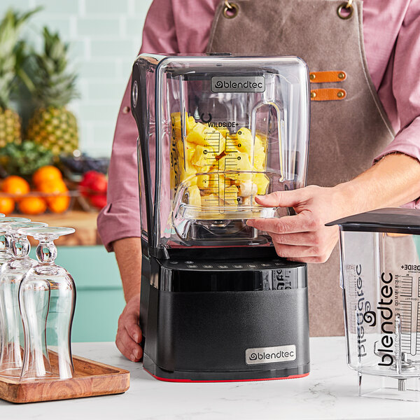 A Blendtec commercial blender with a container of pineapple being used.