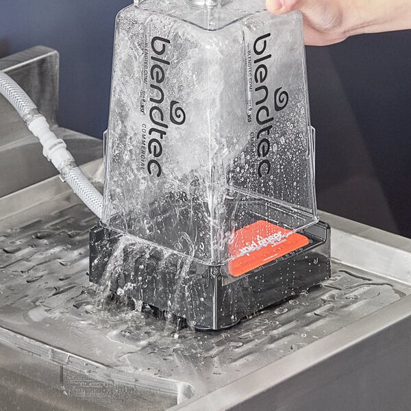 A hand pouring water from a plastic container into a machine.