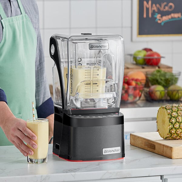 A man using a Blendtec commercial blender to make a yellow smoothie.
