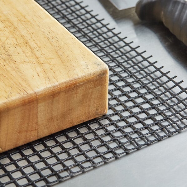 A wood block on a black mesh shelf liner.