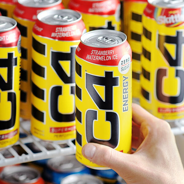 A person holding a yellow and black C4 Energy drink can.