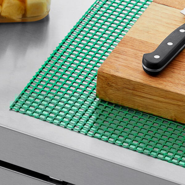 A knife on a green plastic mesh shelf liner.