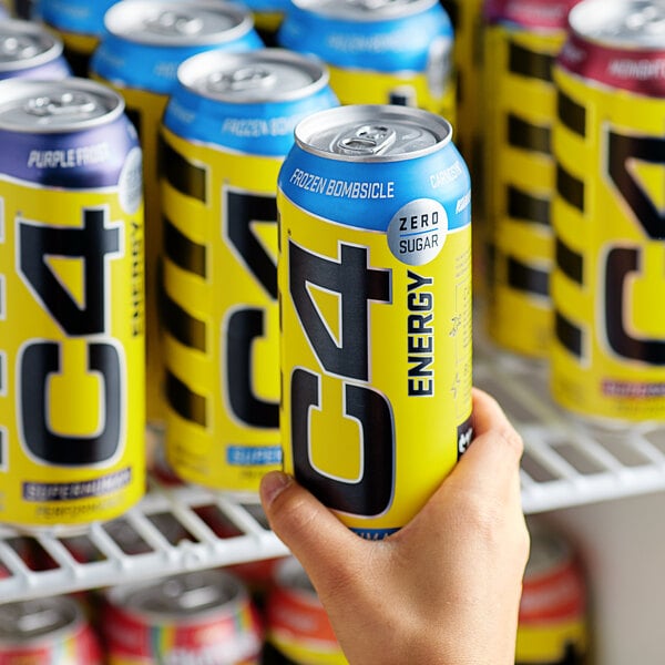 A close up of a hand holding a yellow C4 Energy can with a blue cap.