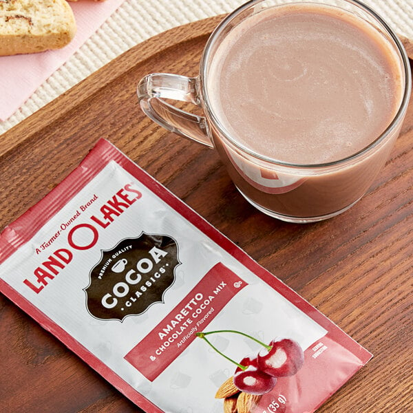 A glass mug of Land O Lakes Amaretto and Chocolate cocoa next to a packet of Land O Lakes Amaretto and Chocolate cocoa.