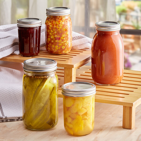 A wooden tray with Choice half-pint mason jars filled with canned food on a table.