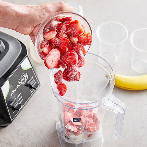 Someone pouring frozen strawberries into a blender