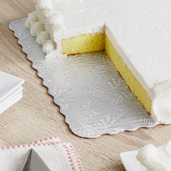 A cake on a table with an Enjay silver laminated corrugated cake board underneath.