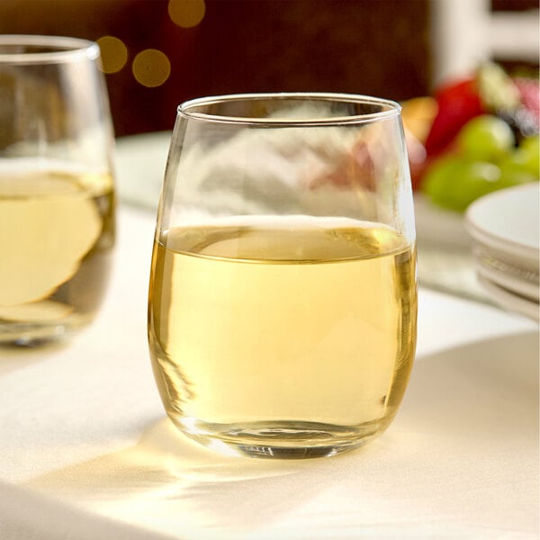 A clear, rounded glass votive candle holder with a 15 oz. capacity, shown on a table setting.