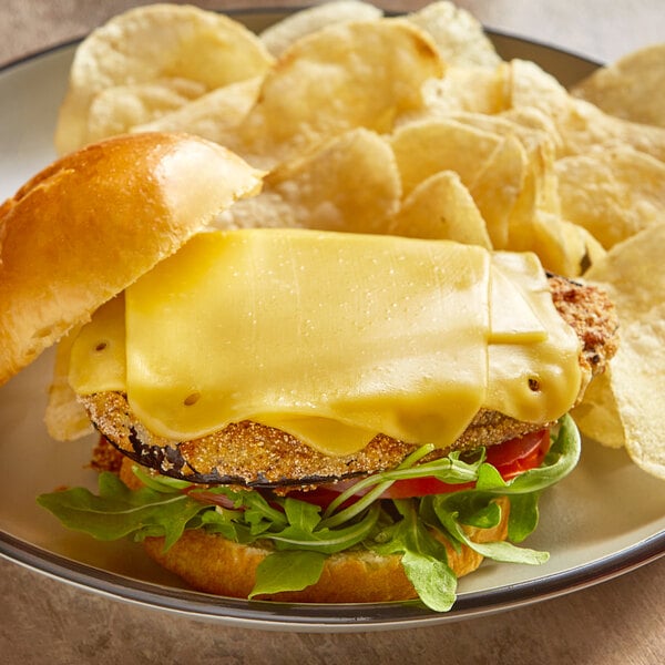 A cheeseburger with Follow Your Heart vegan smoked Gouda cheese and chips on a plate.