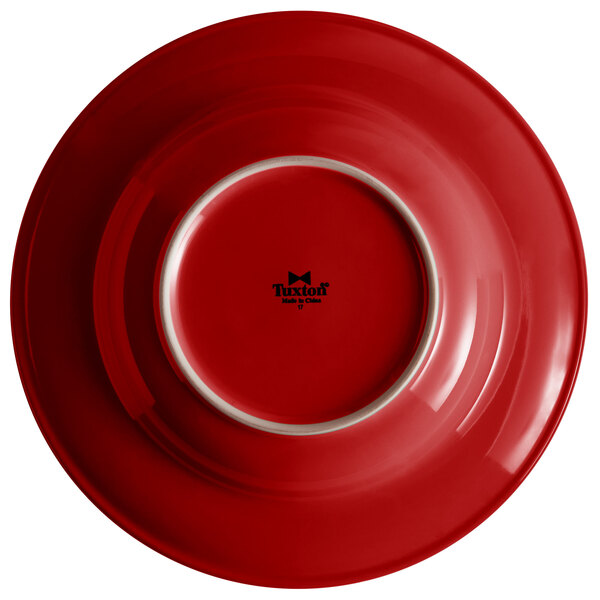 A red Tuxton soup/pasta bowl with a white rim.