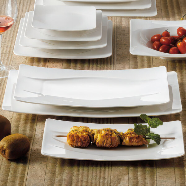 A table set with white rectangular porcelain platters filled with fruit.