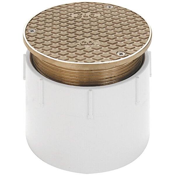 A white plastic pipe with a round lid and a gold square pattern.