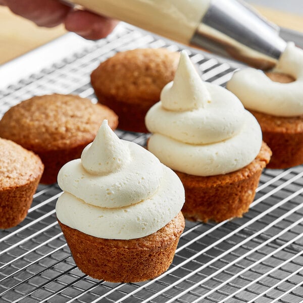 A person icing a cupcake with Gold Medal Ready-to-Spread Cream Cheese Icing.
