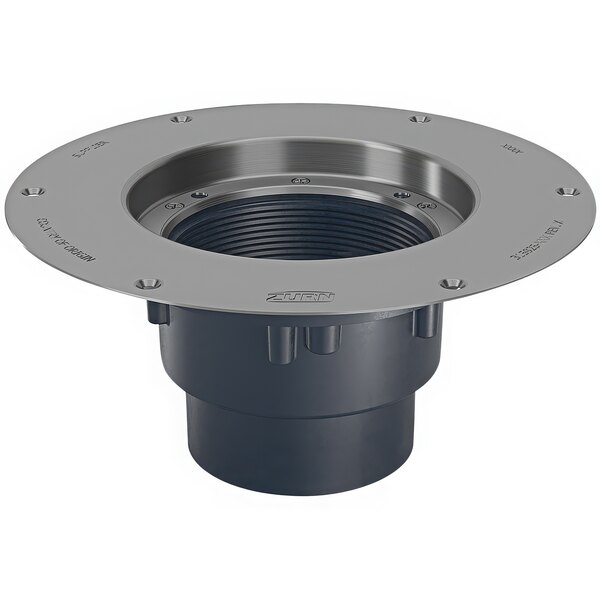 A round metal deck plate with a hole for a metal pipe over a black plastic cleanout.