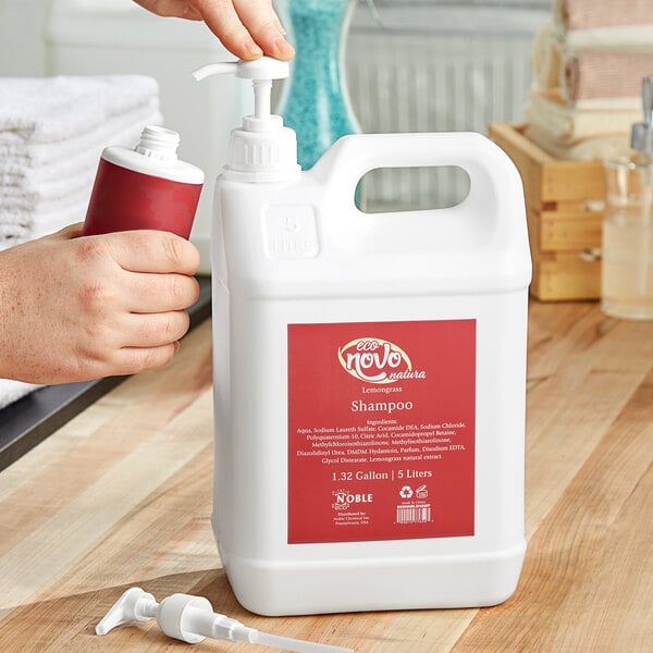 A person pouring Noble Eco Novo Natura shampoo from a white plastic jug with a red label.