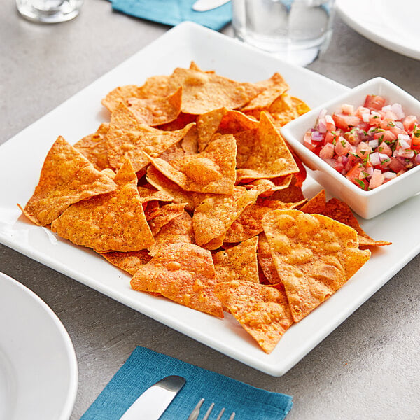 A white plate of Mr. Tortilla chips with a bowl of salsa.