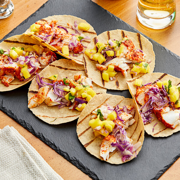 A black plate with four Mr. Tortilla tacos with meat and vegetables.