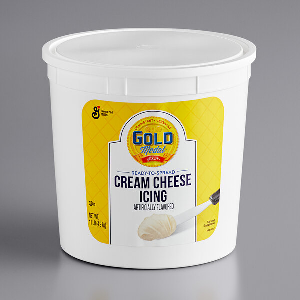 A white container of Gold Medal Ready-to-Spread Cream Cheese Icing with a yellow label and lid.