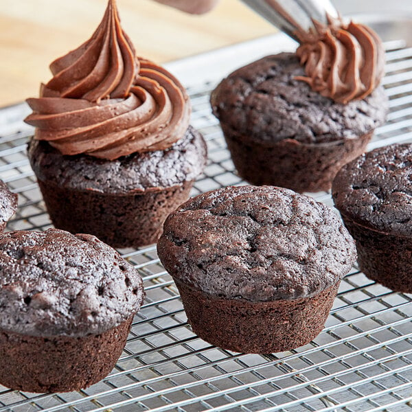 A chocolate cupcake with frosting on a cooling rack.