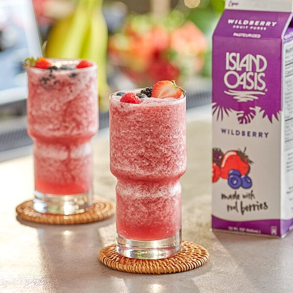 Two glasses of pink wildberry smoothie with strawberries and blueberries.