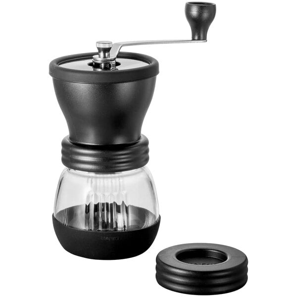 A close-up of a black and clear Hario Skerton coffee grinder with a lid.