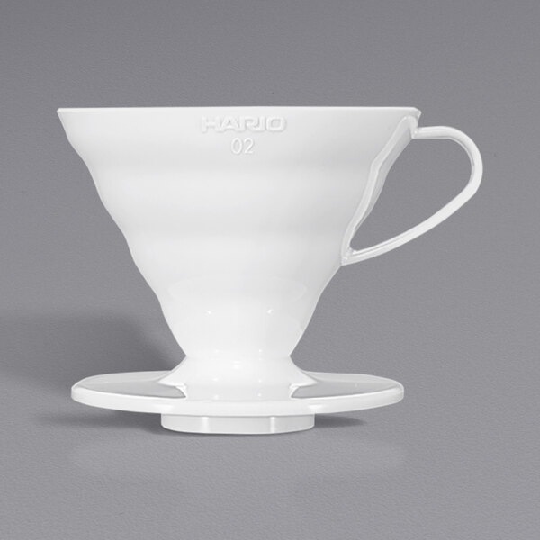 A white Hario V60 coffee dripper on a white surface.