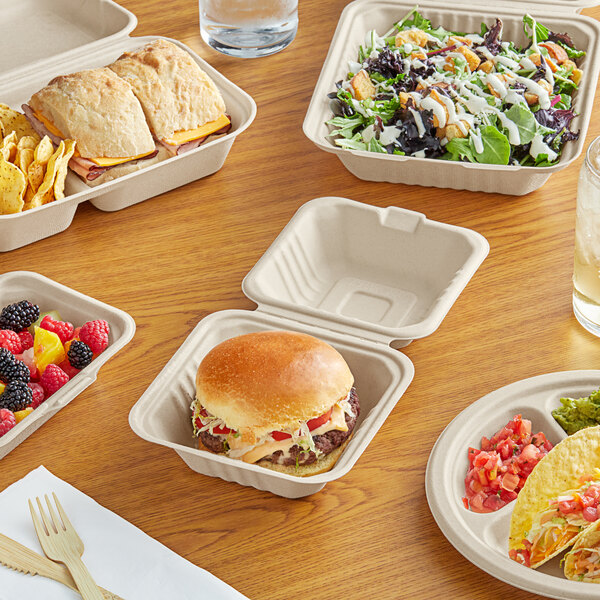 A table with EcoChoice natural bagasse dinnerware holding a variety of food containers and utensils.