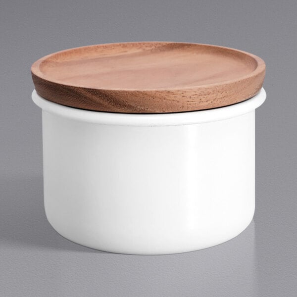 A white Hario enamel canister with a wood lid on a table in a home kitchen.