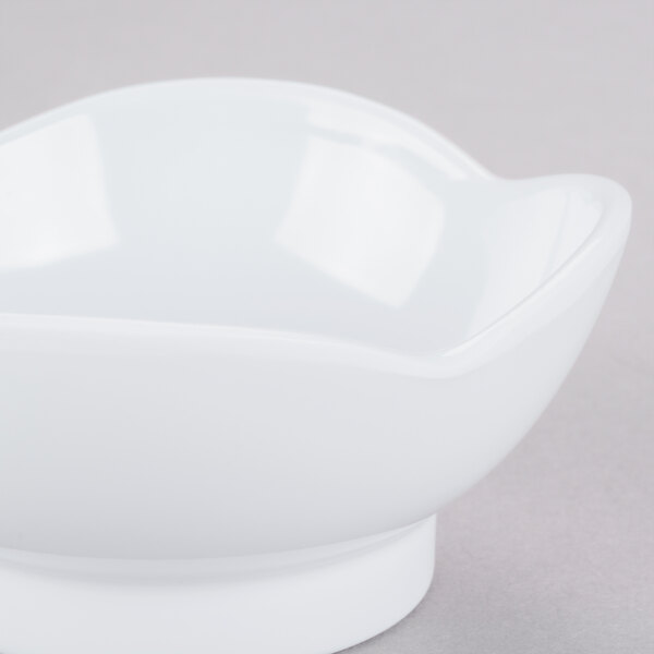 A white scallop shaped melamine bowl on a gray surface.