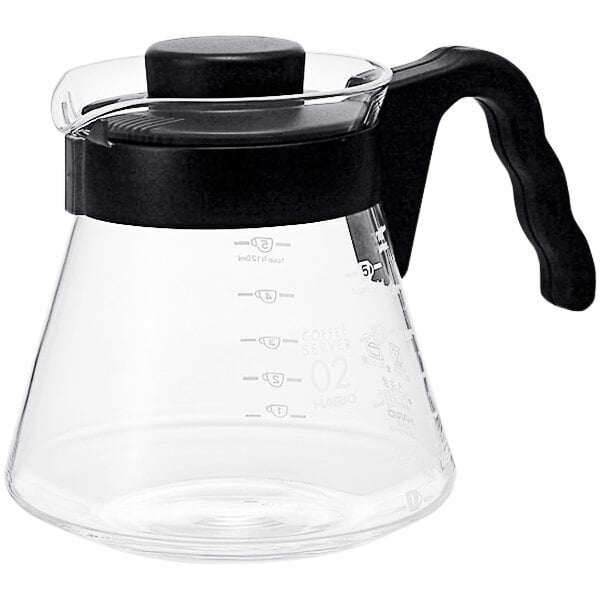 A clear glass coffee pot with a black handle.