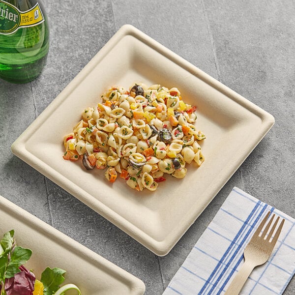 A EcoChoice bagasse square plate with pasta and salad on it next to a bottle of soda.