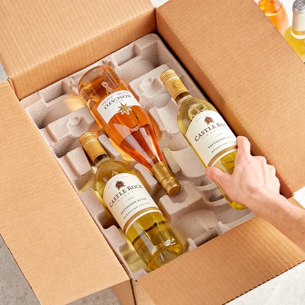 A hand holding a Lavex Molded Fiber 6 Bottle Wine Shipper Kit box with a bottle of wine inside.