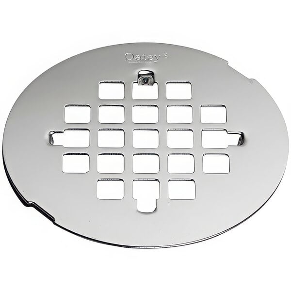 A circular stainless steel Oatey shower drain strainer with squares and circles of holes.